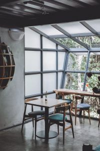 Inviting café interior with wooden furniture and large glass windows letting in natural light.